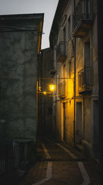 Illuminated street amidst buildings at night