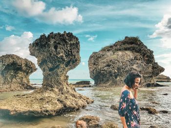 Full length of boy on rock at beach against sky