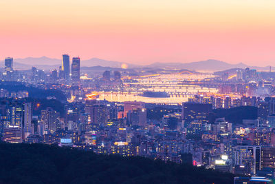 High angle view of illuminated city against sky at sunset