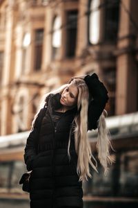 Young woman with umbrella standing against built structure