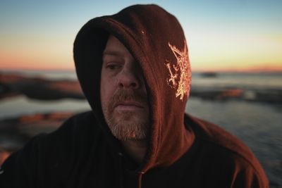 Portrait of young woman looking away against sky during sunset
