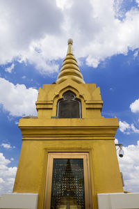 Low angle view of gold stupas against sky