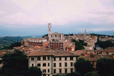 Buildings in town against cloudy sky