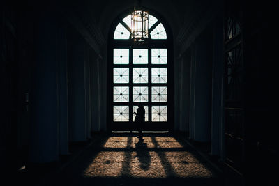 Silhouette woman standing by window in building