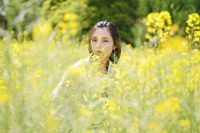 Portrait of woman with yellow flowers on field