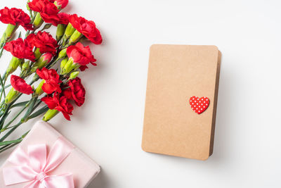 High angle view of red flowers on table against white background