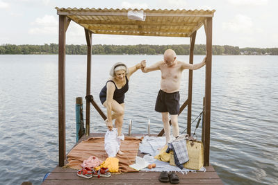 Full length of senior man helping woman in removing shorts at gazebo