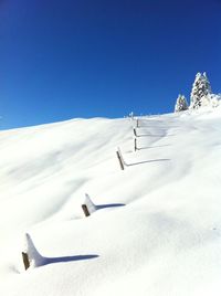 Scenic view of snowy field against clear blue sky