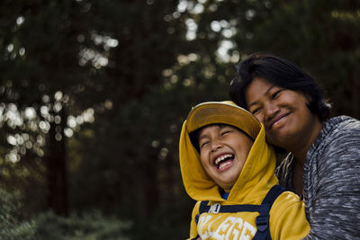 Smiling mother embracing son in forest