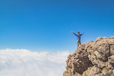 Low angle view of man standing on mountain peak