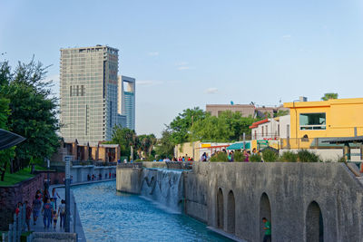 Canal in city against sky