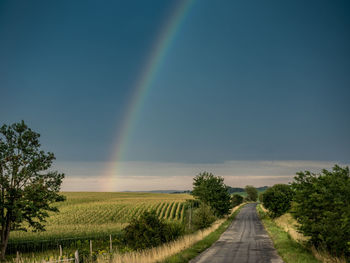 Scenic view of rainbow over field against sky