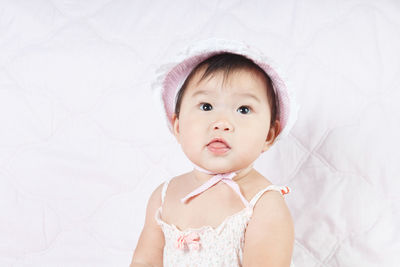 Cute baby girl sitting on bed at home