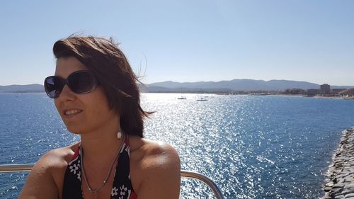 Portrait of young woman in sunglasses at beach against sky