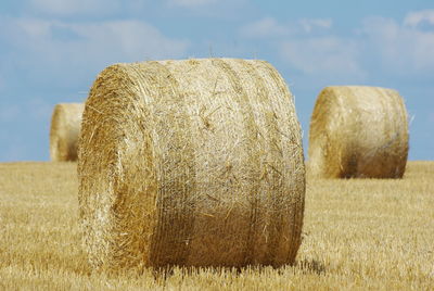 Hay bales on grassy field against sky