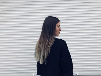 Young woman standing against wall