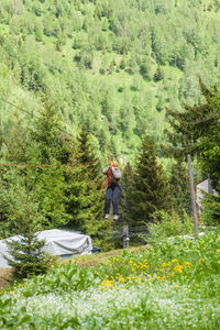 Woman riding zip line over field against mountains