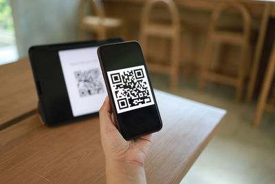 Close-up of hand holding mobile phone on table