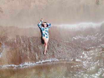 Drone view of woman lying on shore at beach