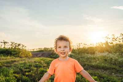 Portrait of smiling boy on field against sky