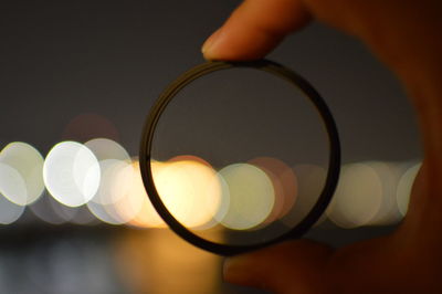 Cropped hand holding lens at night