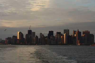 Sea and cityscape against sky during sunset