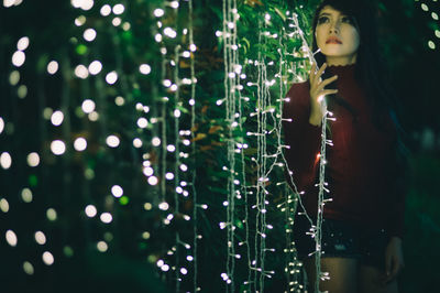 Young woman standing by christmas lights