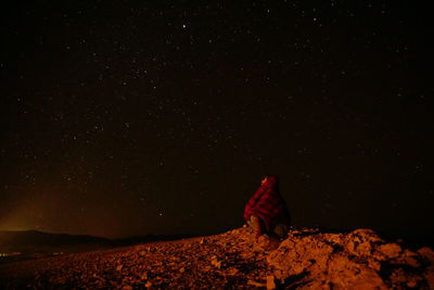 Rear view of person on field against sky at night