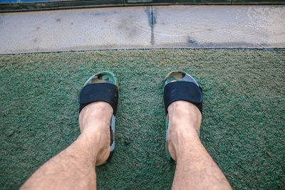 Low section of man wearing shoes on grass