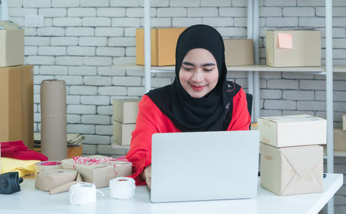 Portrait of a smiling young woman using phone