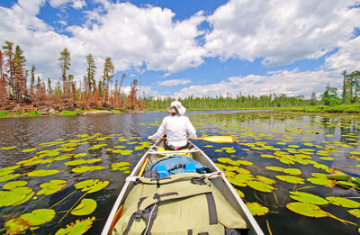 Rear view of woman floating on lake against sky