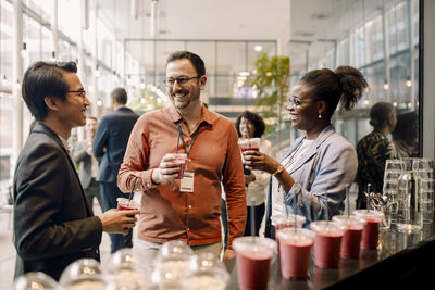 Smiling male entrepreneur having drinks with delegates during seminar at convention center
