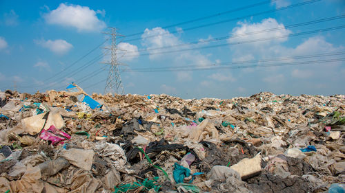 Stack of garbage by house against sky