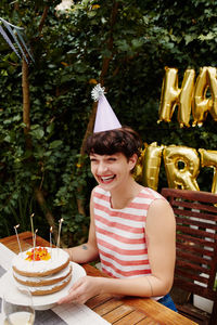 Smiling woman sitting by birthday cake