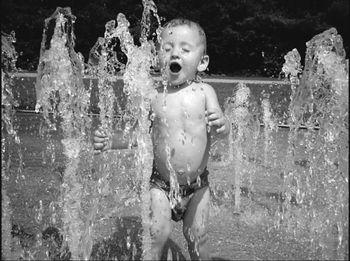 Full length of shirtless boy standing in water