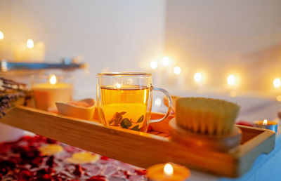 Herbal mint tea on bathtub tray with candles, lavender and salt during spiritual aura cleansing bath