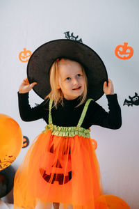 Children's halloween - a girl in a witch hat and a carnival costume with airy orange and black 