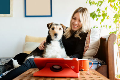 Portrait of young woman with dog sitting at home