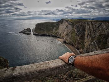 Midsection of man on rock by sea against sky