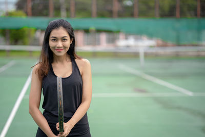 Portrait of smiling tennis player standing in court