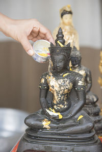 Close-up of hand pouring water on statue