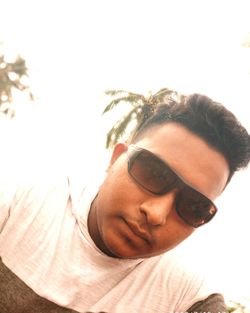 Close-up portrait of young man wearing sunglasses against sky