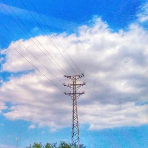 Low angle view of electricity pylon against blue sky