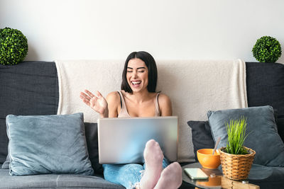 Young woman using mobile phone while sitting on sofa at home