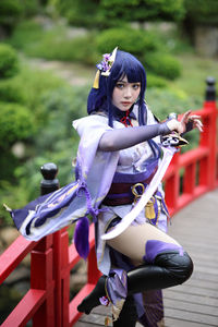 Portrait of young woman sitting on railing