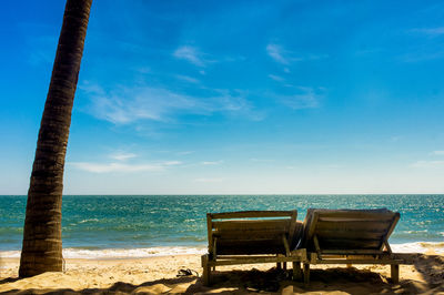 Deck chairs on beach against blue sky