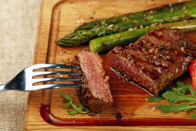 Close-up of grilled meat and asparagus on cutting board