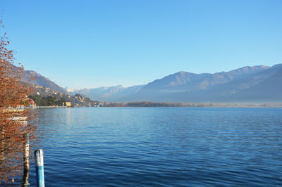 Scenic view of lake and mountains against clear blue sky