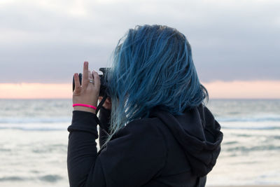 View of woman photographing sea against sky