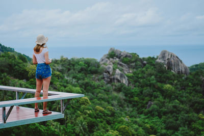 Rear view of woman standing on observation point looking at sea